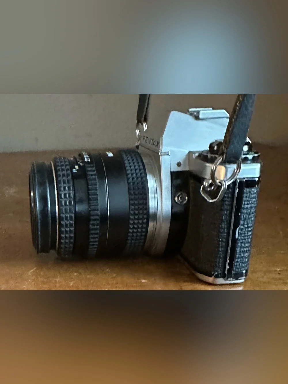 Pentax Silver and Black SLR Camera with Black Lens Cap and Colorful Strap